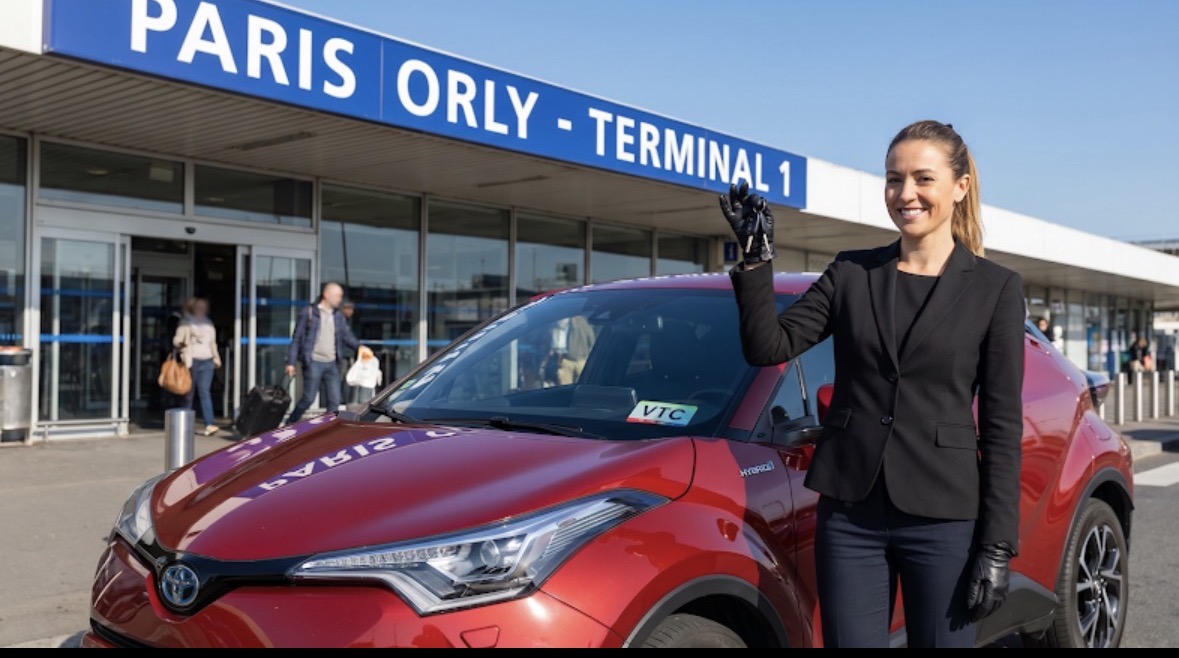 Chauffeure First Lady VTC devant l’aéroport Paris-Orly avec Toyota rouge